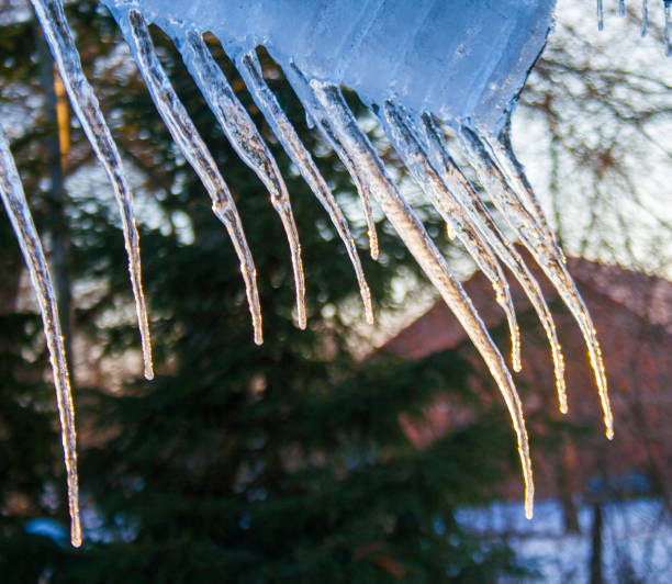 istock beautiful icicles shine in sun against blue sky. spring landscape with ice icicles hanging from roof of house 1176144530