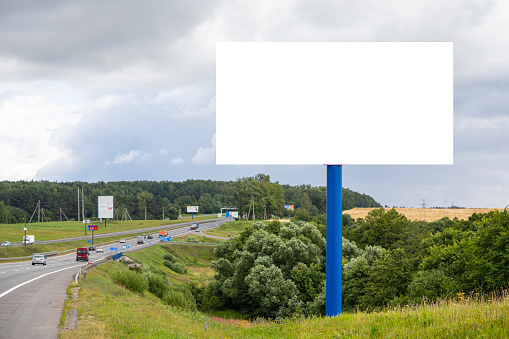 White blank board mock-up along highway against fields