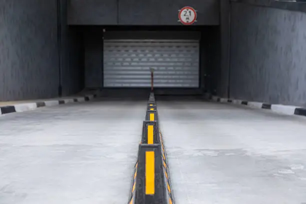 Access to underground garage with roller-shutter door and road dividers with yellow sticks