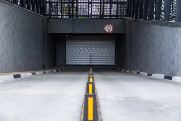 Entrance to underground car parking with roller-shutter door and road dividers