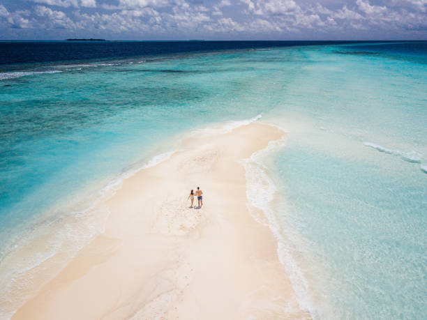 young adult couple standing on a sandbank against turquoise water in maldives - sandbar imagens e fotografias de stock