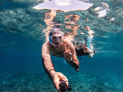 Young adult couple making an underwater selfie.