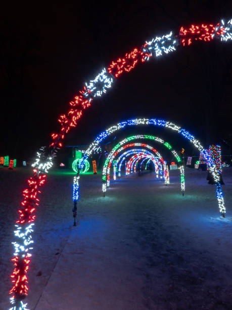 istock Colorful striped LED string light wrapped arches extend over a walkway at a holiday lights festival. 1176159049