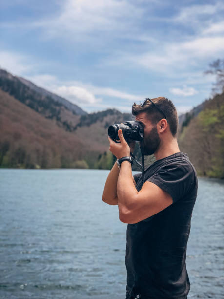 istock Man photographing lake 1176159581