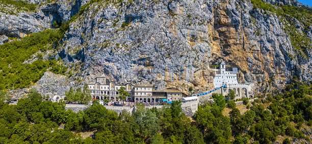 Aerial view of The Monastery of Ostrog, Serbian Orthodox Church situated against an almost vertical background, high up in the large rock of Ostroška Greda, in Montenegro. Dedicated to Saint Basil of Ostrog. Winding roads
