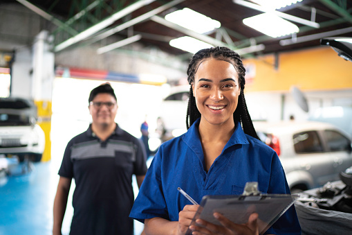 Auto mechanic woman portrait with customer on background at auto repair shop