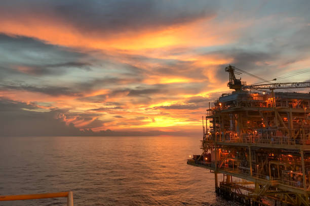 plataforma de construção offshore para exploração e produção de petróleo e gás com ponte no tempo da noite para a energia do conceito mundial. - oil pumping unit at sunset time - fotografias e filmes do acervo