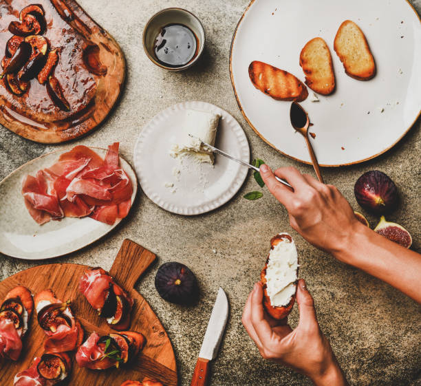 istock Crostini with prosciutto, figs and womans hands spreading cheese 1176171562