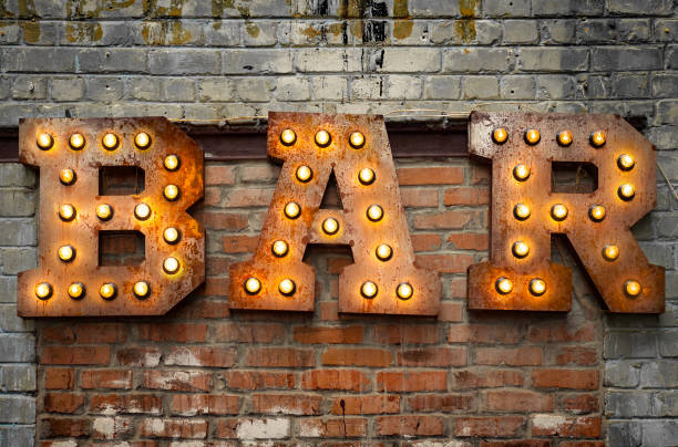 inscripción de grandes letras metálicas decoradas con bombillas brillantes en la pared de ladrillo - metallic wall brick glowing fotografías e imágenes de stock