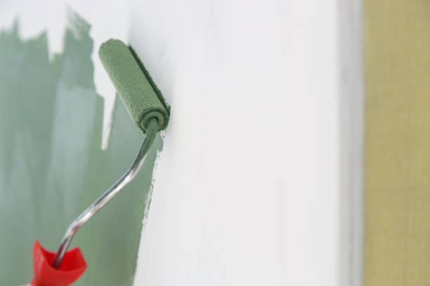 istock Paint roller. Process of painting with green paint over a white wall. 1176178099