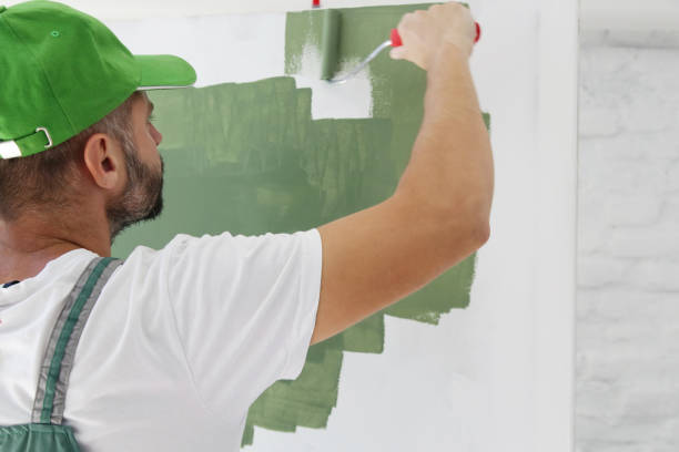 istock Man painting with green paint over a white wall 1176179652