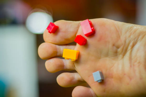a man foot step on colored toy brick on ground and pain full. High resolution image gallery.