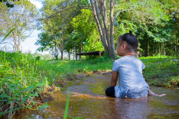 Asian Children playing  barefoot in stream water, catch a fish play mud and sand. High resolution image gallery.