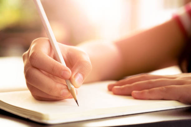 istock Education concept.Close up of a female hand using a pencil writing  ,drawing on a white book 1176185884