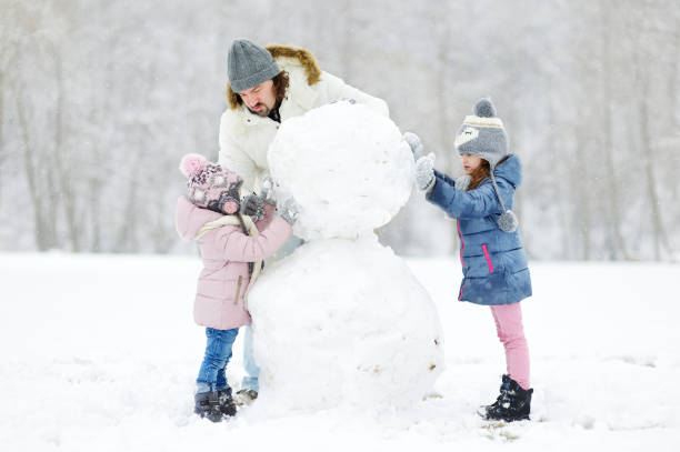 istock Young father and his daughters building a snowman 1176189168
