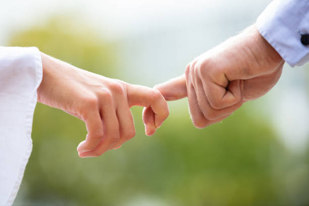 Close-up Of Couple Holding Index Fingers Close-up Of Loving Couple Holding Each Other's Finger Against Blurred Background co dependent relationship stock pictures, royalty-free photos & images