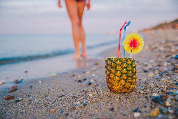 Pineapple lying on sun chair on the sand against turquoise sea. Relaxing. Tropical summer vacation concept.
