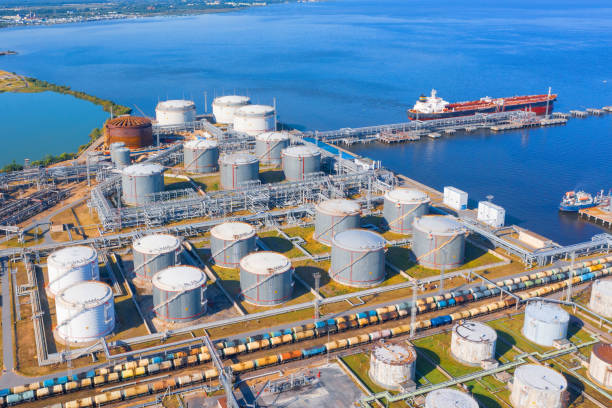 aerial view of large fuel storage tanks at oil refinery industrial zone in the cargo seaport, and ship tanker at unloading. - porto built structure commercial dock port wine imagens e fotografias de stock