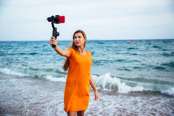 istock Young woman vlogging from beach 1176208505