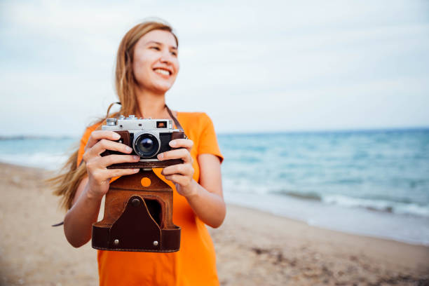 istock Woman holding retro camera on the beach 1176208589