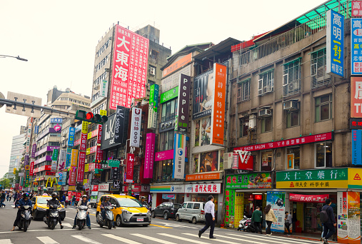 Taipei, Taiwan- May 2019: View of Taipei street and crosswalk, with cars and motorcycles stopping at a red light.