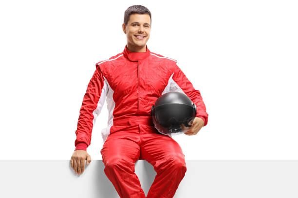 istock Car racer in a suit holding a helmet and sitting on a panel 1176220104