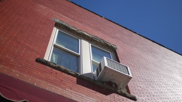 Establishing shot of second story apartment with air conditioner unit sticking out of window