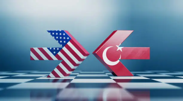 Two arrows textured with American and  Turkish flags colliding on black and white chessboard. Politics and checkmate concept. Horizontal composition with selective focus and copy space.