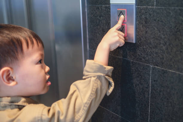 アジアの3 -4歳の幼児の男の子は、エレベーター/エレベーターボタンを押そうとエレベーターの前に立って - 3 4 years ストックフォトと画像