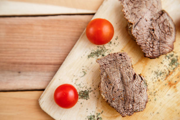 chunks of deep-fried meat, steak on a wooden tray with spices and cherry tomatoes