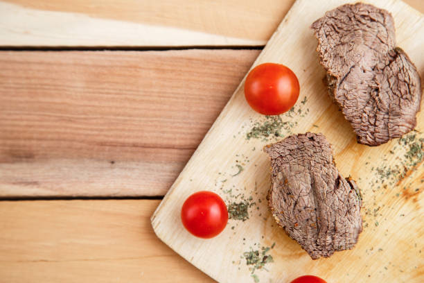 chunks of deep-fried meat, steak on a wooden tray with spices and cherry tomatoes