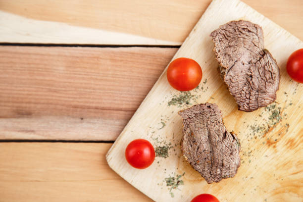 chunks of deep-fried meat, steak on a wooden tray with spices and cherry tomatoes