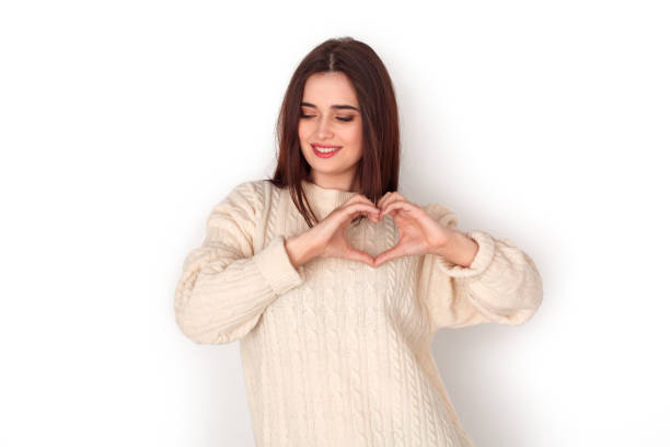 istock Young woman studio standing isolated on white showing heart shape shy 1176237532