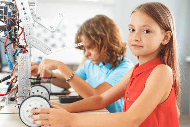istock Robotics. Children sitting having class making robots girl close-up looking camera curious 1176237536
