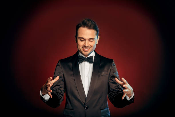 istock Professional Occupation. Showman in suit standing isolated on wall showing trick smiling cheerful 1176237543