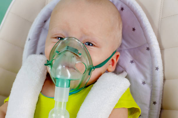 A child in a chair with an inhaler. Treatment and therapy at home. A child in a chair with an inhaler. Treatment and therapy at home pediatric nebulizer mask stock pictures, royalty-free photos & images
