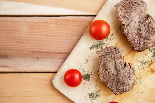 chunks of deep-fried meat, steak on a wooden tray with spices and cherry tomatoes