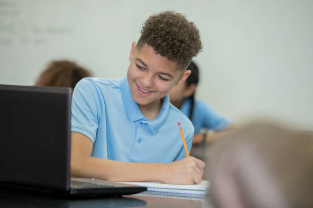 istock Young male student smiles while writing essay in classroom 1176252888
