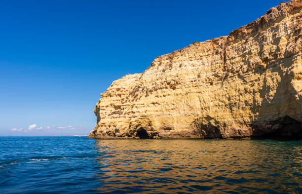 Dramatic Algarve cliffs and caves near Carvoeiro in Portugal This dramatic limestone coastline is formed of sea pillars, fragile rock arches and hidden grottos. Photographed from a boat during a sunny Summer morning. beautiful beach in carvoeiro algarve portugal stock pictures, royalty-free photos & images