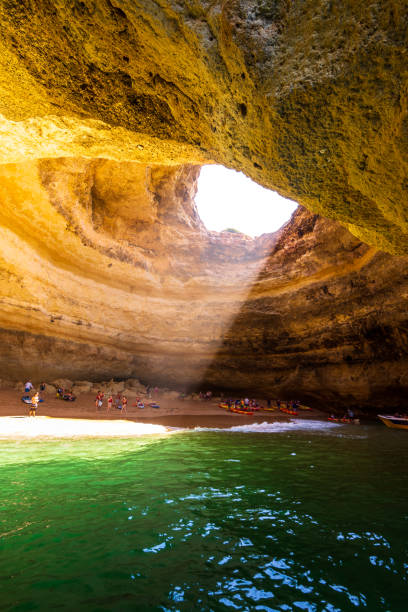 Tourists relax inside Benagil Cave along Algarve coast in Portugal The Benagil Cave is one of the most beautiful destinations along the Algarve's dramatic limestone coastline. Photographed from a boat during a sunny Summer morning. algar de benagil photos stock pictures, royalty-free photos & images