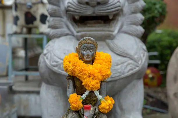 Photo of Woman statue beckoning happy with yellow flower in Thai temple, focus selective.