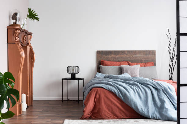 istock Copy space on empty white wall of rustic bedroom interior with king size bed with orange and pastel blue bedding 1176272660