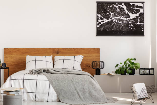 Copy space on white wall with black map in modern bedroom with king size bed with wooden headboard