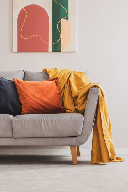 istock Yellow blanket on grey sofa with orange and black pillows 1176273710