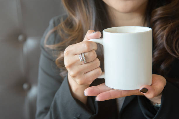 giovane donna che tiene una tazza di caffè bianco con due mani all'aperto. - caucasian foto e immagini stock