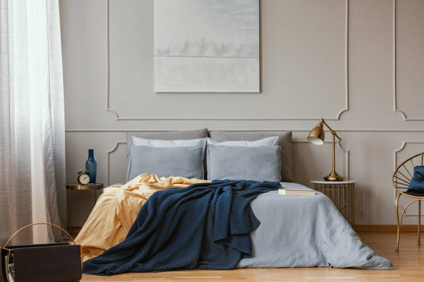 Dark blue and orange blankets on comfortable double bed in grey stylish bedroom Dark blue and orange blankets on comfortable double bed in grey stylish bedroom shaping room stock pictures, royalty-free photos & images