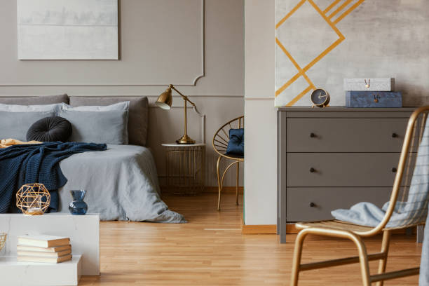 istock Trendy bedroom interior with grey commode and golden chair 1176275789