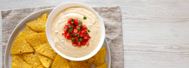 Homemade cheesy dip in a bowl, yellow tortilla chips, top view. Flat lay, overhead, from above. Space for text. Homemade cheesy dip in a bowl, yellow tortilla chips, top view. Flat lay, overhead, from above. Space for text. cheese dip stock pictures, royalty-free photos & images