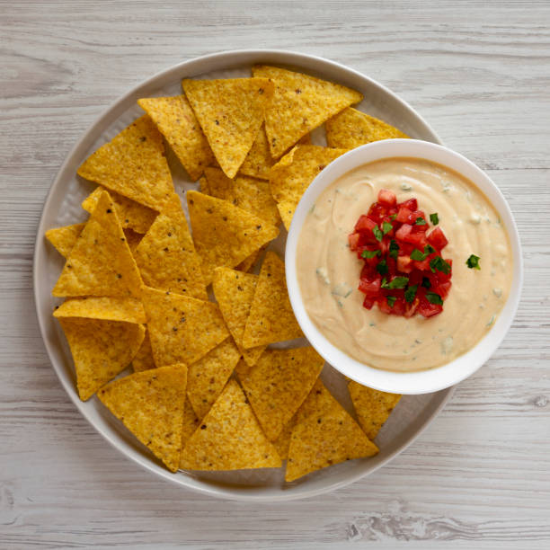 Homemade cheesy dip in a bowl, yellow tortilla chips, overhead view. Flat lay, top view, from above. Close-up. Homemade cheesy dip in a bowl, yellow tortilla chips, overhead view. Flat lay, top view, from above. Close-up. cheese dip stock pictures, royalty-free photos & images