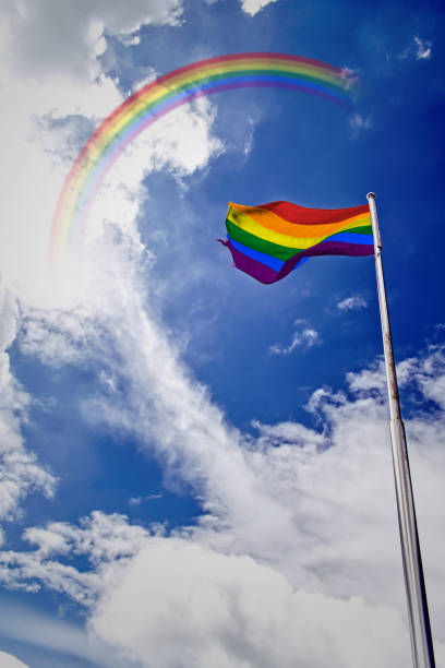 istock Rainbow flag waving in the wind under blue sky with rainbow. 1176284622